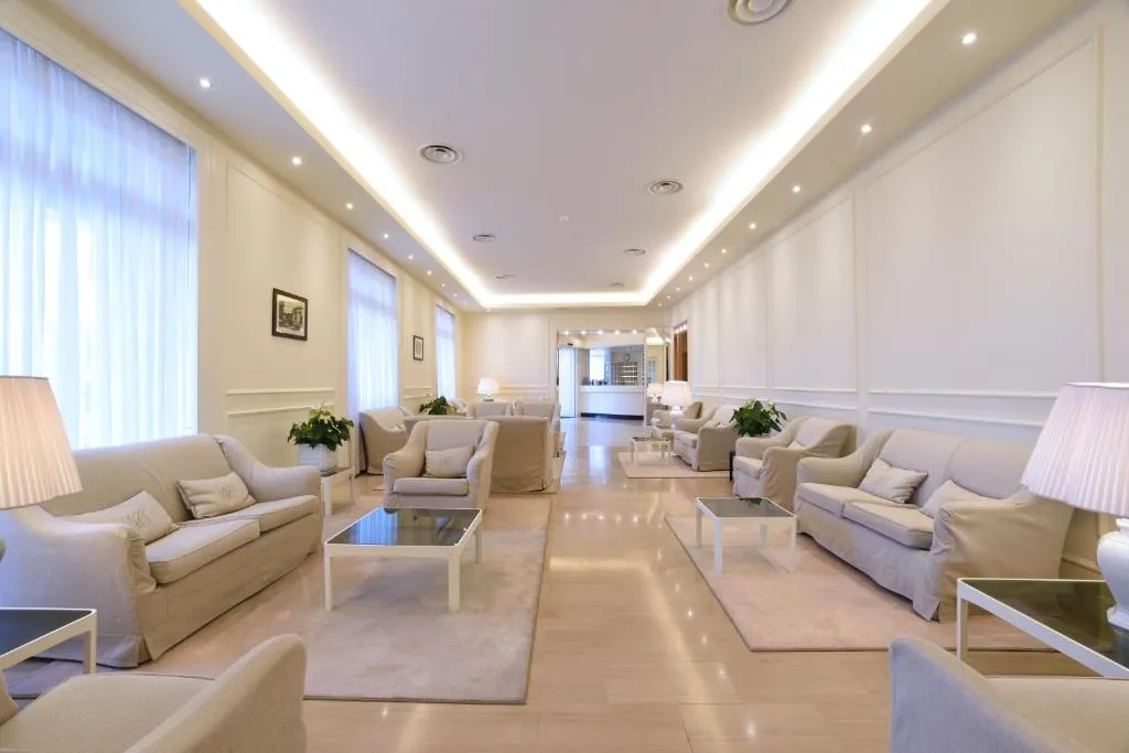 Ampia sala soggiorno con divani e poltrone beige, lampade e arredi eleganti