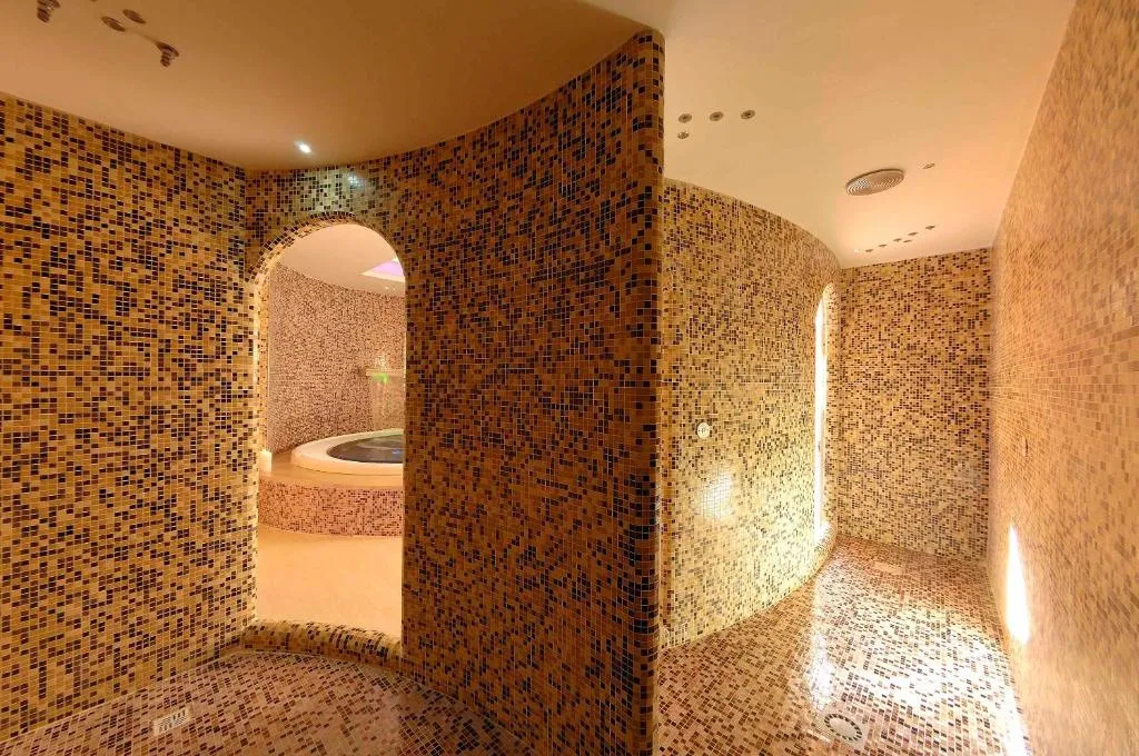 Percorso benessere con pareti a mosaico e vasca idromassaggio sullo sfondo