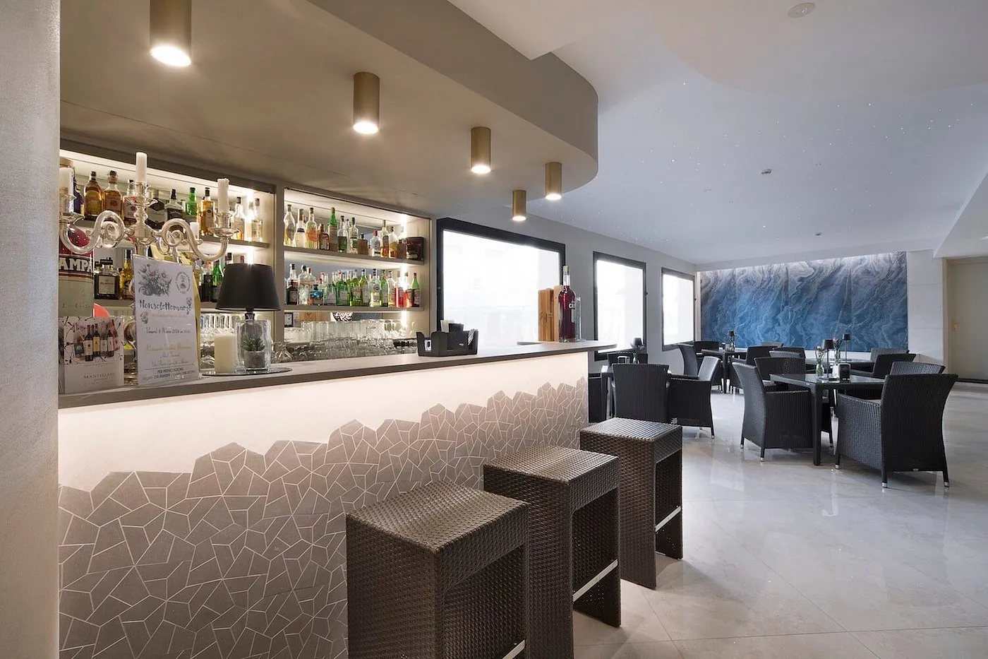 Bar moderno dell'hotel con bancone illuminato, sgabelli e area lounge
