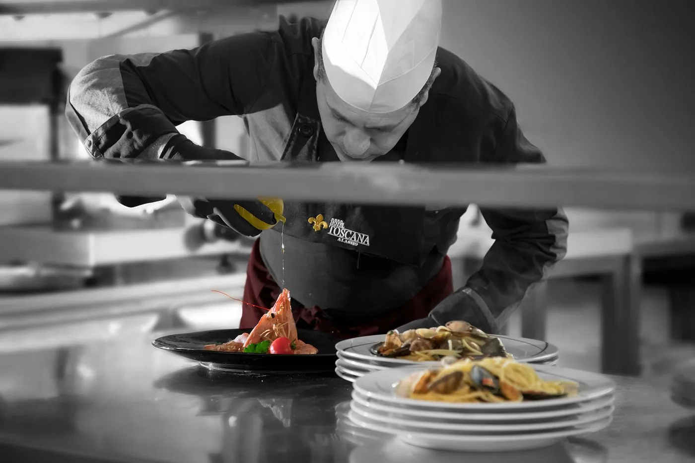 Chef dell'Hotel Toscana che impiatta un piatto di pesce in cucina